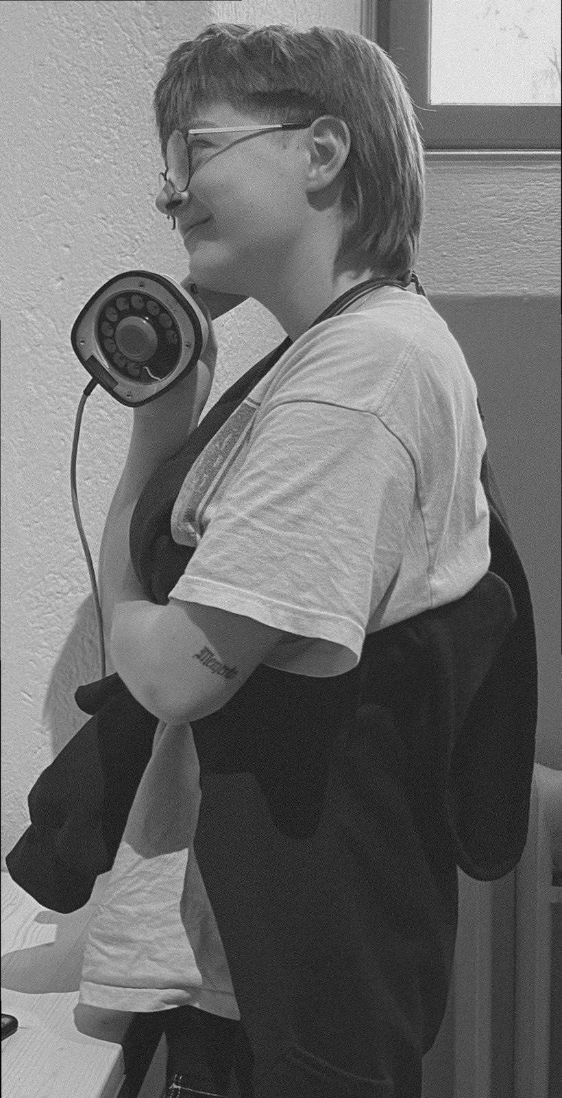 A visitor in profile, holding the Ericofon-style handset to their ear, smiling.