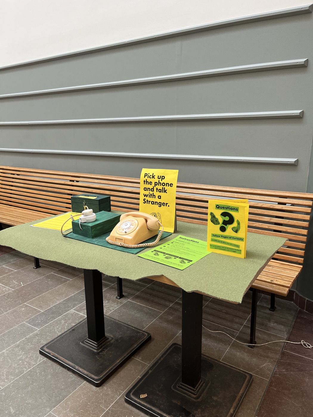 The Dialog on green felt by a wooden bench, with yellow posters and a question-mark sign.