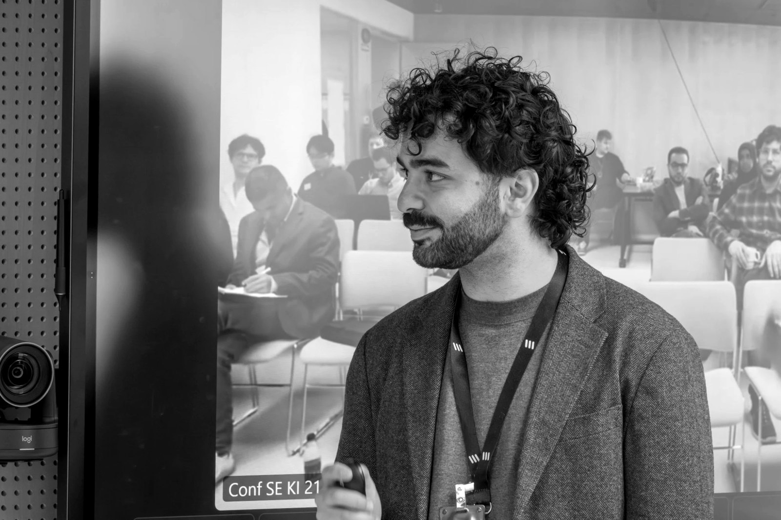 Nikos presenting at the Ericsson Developer Conference, clicker in hand, with the remote audience in another office on the screen behind him.