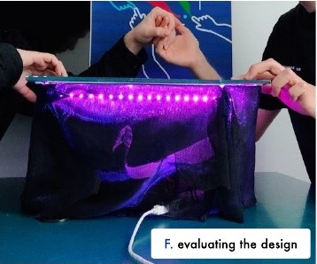 F: the finished table glowing purple underneath while two people touch it.